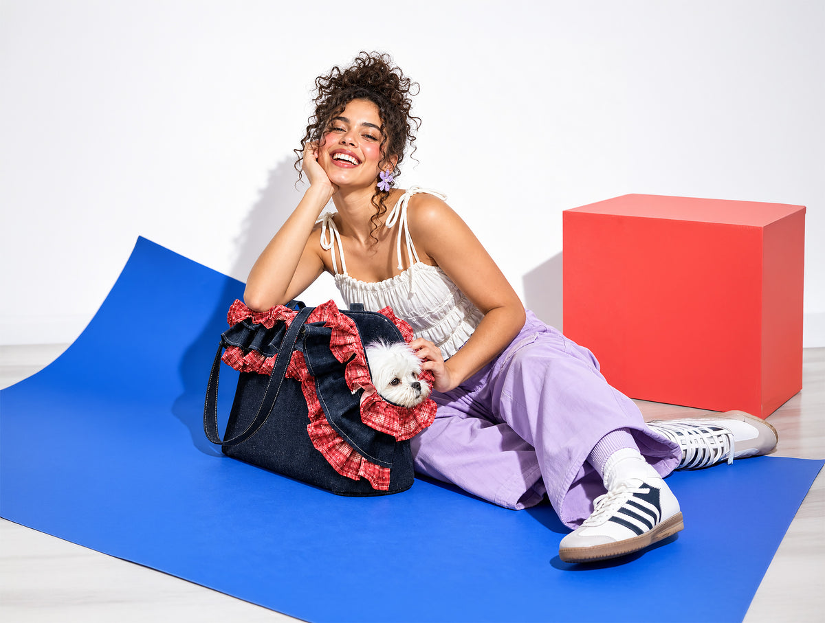 A pet parent with a small dog in the Rumi denim carrier